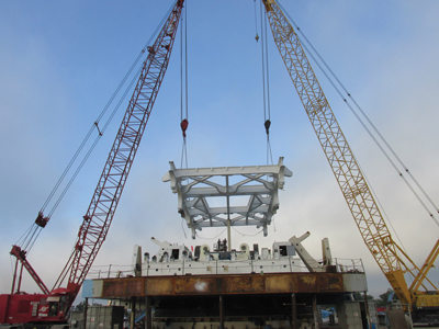 A two-crane lift setting the modified superstructure on the machine.